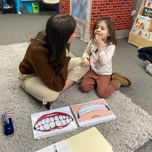 speech therapist working with a young child sitting on the office floor